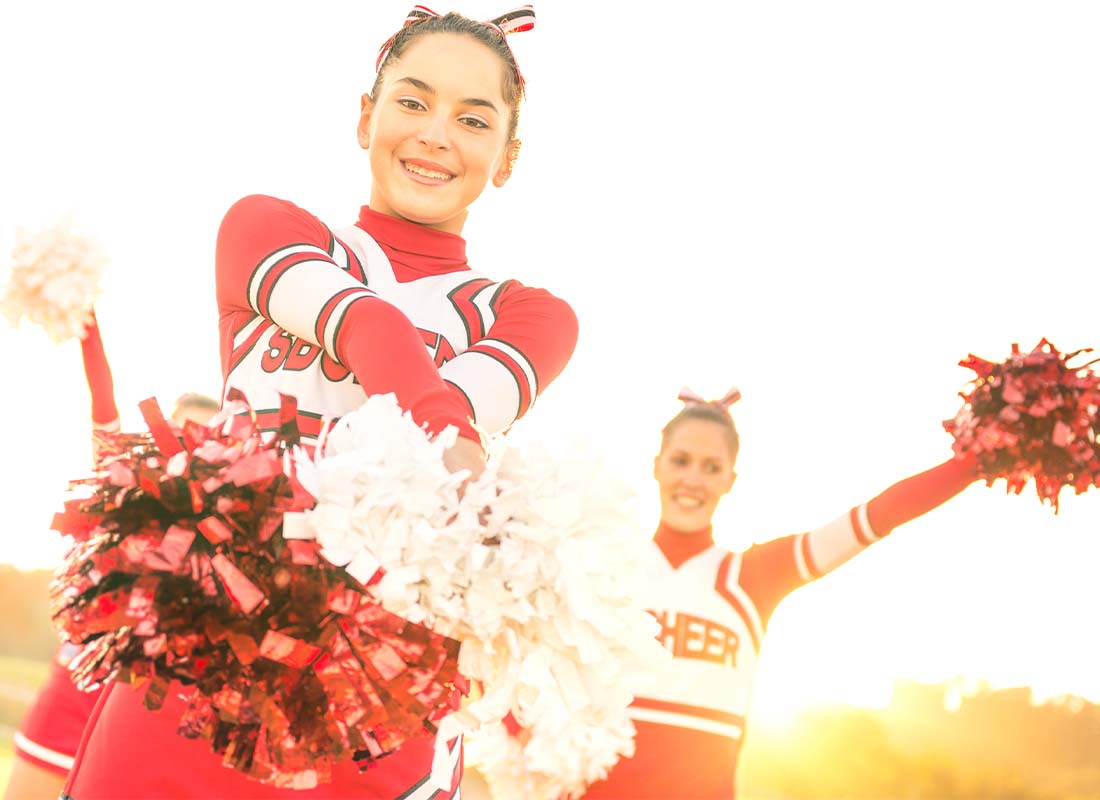 Cheer Gym Insurance - Group of Cheerleaders Performing Outdoors at a High School Championship Game at Sunset